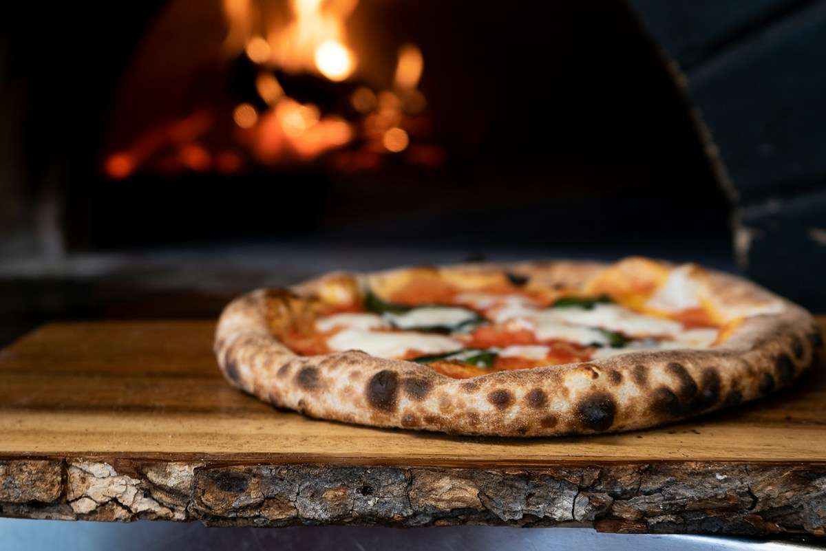 Pizza artesanal com queijo e folhas de manjericão